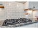 Close-up of a gas cooktop with stainless steel knobs and a white subway tile backsplash at 625 Highland Ridge Pt, Clover, SC 29710