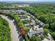 Community aerial showcasing rows of townhomes nestled among colorful trees, near a road and green spaces under a blue sky at 5212 Berkeley View Cir, Charlotte, NC 28277