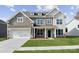 Two-story house with gray siding, stone accents, and a three-car garage at 223 E Warfield Dr, Mooresville, NC 28115