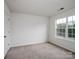 A bedroom with neutral carpet and paint and one large window at 2715 Ballade Dr, Matthews, NC 28105