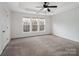 An airy bedroom with neutral carpet, trim and paint with a ceiling fan and three windows at 2715 Ballade Dr, Matthews, NC 28105