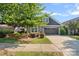 Charming home showcasing a well-kept lawn, a gray garage door, a manicured garden, and mature trees at 16115 Lakeside Loop Ln, Cornelius, NC 28031