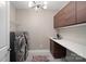 Modern laundry room with front-loading machines, white countertop, and wood cabinets at 16115 Lakeside Loop Ln, Cornelius, NC 28031