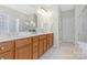 Bathroom boasts double sinks, wood cabinets, tile floors, and decorative lighting; with glass shower in background at 3015 Duclair Ln, Fort Mill, SC 29707