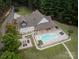 An aerial view showcasing a home's backyard with pool, outdoor seating, a fire pit, and lush landscaping at 1046 Sutton Spring Rd, York, SC 29745