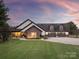 Home's exterior with stone accents, manicured lawn, and a three-car garage, all in a tranquil setting at 1046 Sutton Spring Rd, York, SC 29745