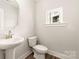 Modern powder room features a pedestal sink, a toilet, and a window for natural light at 429 Nathaniel Way # Brx0032, Charlotte, NC 28213