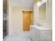 This bathroom features a sliding wooden door, white cabinets, a vanity and a tiled shower with gray accents at 751 White Jenkins Rd, Bessemer City, NC 28016