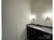 Elegant bathroom featuring a dark vanity with stone countertop, a sink, and modern sconces at 139 Poplar Grove Rd, Mooresville, NC 28117