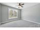 Bright bedroom with grey carpeting, ceiling fan, and a large window at 2610 Henry Baucom Rd, Monroe, NC 28110