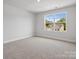 Bright, carpeted bedroom with a large window offering a view of the neighborhood and house across the street at 1051 Bull Dog Ln, Wingate, NC 28174