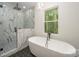 Bathroom with freestanding bathtub, walk-in shower, and marble tile at 312 General As Johnston St, Stanley, NC 28164