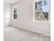 Bedroom with neutral carpet, white walls, trim, natural light from two windows, and a door at 332 Shinnville Rd, Mooresville, NC 28115