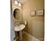 Powder room features pedestal sink, framed art, round mirror, towel rack, and neutral wall paint at 152 Bridge Pointe Ln, Hickory, NC 28601