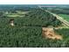 Captured from above, it highlights a dense forest with a pond and roadway under construction at 1021 Baylor Grv, Monroe, NC 28110