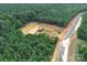 This aerial view shows a road and pond under construction amidst a lush, wooded landscape at 1021 Baylor Grv, Monroe, NC 28110