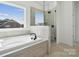 Modern bathroom featuring a soaking tub, tiled shower, and a large window at 2140 Indigo Branch Rd, Indian Land, SC 29707