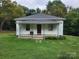 Quaint single-story home with a inviting front porch, set on a green lawn, and lush trees in the background at 113 Fairview St, Clover, SC 29710