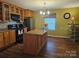 Traditional kitchen boasts wooden cabinets, stainless appliances, island, hardwood floors, and a stylish chandelier at 113 Fairview St, Clover, SC 29710