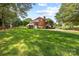 Backyard view of the brick home with green lawn, mature trees, and a large driveway leading to a garage at 102 Sleaford Ct, Dallas, NC 28034