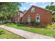 Charming brick home featuring arched windows, lush landscaping, and a well-maintained lawn along the sidewalk at 102 Sleaford Ct, Dallas, NC 28034