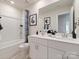 Well-lit bathroom with double vanity, framed art, and a shower/tub with a blue patterned curtain at 153 Shepherds Landing Dr, Mooresville, NC 28115