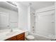 Bright full bathroom featuring tub-shower, wooden vanity, and white toilet at 9345 Hamel St, Charlotte, NC 28215