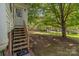 Backyard with wooden stairs leading to a white door and a spacious lawn at 405 7Th St, Spencer, NC 28159