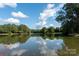 A tranquil lake reflects the blue sky and clouds, surrounded by lush trees, showcasing the property's serene setting at 1873 Farrow Dr, Rock Hill, SC 29732