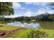A picturesque lake with a home on the far shore is surrounded by green lawns and vibrant foliage at 1873 Farrow Dr, Rock Hill, SC 29732