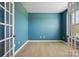 Stylish bedroom with vibrant blue walls, wood-look flooring, and large windows for natural light at 939 Cobbled Way, Fort Mill, SC 29715