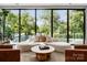 Bright living area featuring a curved sofa, leather chairs, and a large window overlooking the backyard and pool, promoting an inviting atmosphere at 2116 Woodhaven Rd, Charlotte, NC 28211