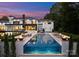 Backyard pool with a water feature, surrounded by lounge chairs, manicured landscaping and twilight sunset at 2116 Woodhaven Rd, Charlotte, NC 28211