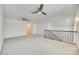 Bright bonus room featuring neutral carpet, two ceiling fans, and staircase with decorative wrought iron railing at 4023 Home Grown Way, Lake Wylie, SC 29710