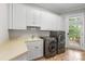 Bright laundry room featuring white cabinets, a utility sink, and modern washer and dryer units at 130 Stonewall Beach Ln, Mooresville, NC 28117