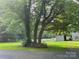 Picturesque property featuring lush greenery, mature trees, a white fence, and a charming barn in the background at 1409 Trinity Church Rd, Monroe, NC 28112