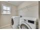 Modern laundry room featuring a large window, washer, dryer, tile floor and wire rack at 16840 Rudence Ct, Charlotte, NC 28278