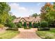 Stone house with circular driveway, manicured landscaping, and a terracotta roof at 4231 Fox Brook Ln, Charlotte, NC 28211