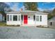 Charming white house with red door, gray gravel driveway, and well-maintained landscaping at 83 Woodsdale Se Pl, Concord, NC 28025