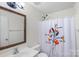 Clean bathroom with floral shower curtain and mirrored vanity at 10423 Brawley Ln, Charlotte, NC 28215