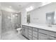 Bathroom with dual vanity, gray cabinets, large mirror, and tiled shower with glass door at 1617 Blanche St, Charlotte, NC 28262