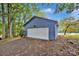 Detached two car garage with white garage door and blue siding in a wooded area at 470 Lakeview Shores Loop, Mooresville, NC 28117