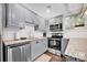 Well-lit kitchen features stainless steel appliances, granite counters, tile backsplash, and gray cabinetry at 470 Lakeview Shores Loop, Mooresville, NC 28117