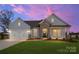 Charming single-story home at sunset featuring stone accents, a two-car garage, and a well-manicured lawn at 3228 Gavin Ln, Harrisburg, NC 28075