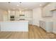 Bright kitchen features an island with seating, stainless steel appliances, and white cabinets and backsplash at 3228 Gavin Ln, Harrisburg, NC 28075