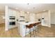 Bright kitchen features an island with seating, stainless steel appliances, and white cabinets and backsplash at 3228 Gavin Ln, Harrisburg, NC 28075