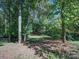 Backyard area with mature trees and a small clearing with grass and fallen leaves at 907 Weymouth Dr, Gastonia, NC 28056