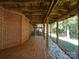 Outdoor space underneath a house deck with brick wall and access to lush trees at 907 Weymouth Dr, Gastonia, NC 28056