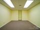 Empty room with yellow walls, wall-to-wall carpet, and a built-in shelving unit at 907 Weymouth Dr, Gastonia, NC 28056