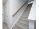 Carpeted staircase with wooden handrail, white walls, and natural light at 1007 Freeman View Dr, Albemarle, NC 28001